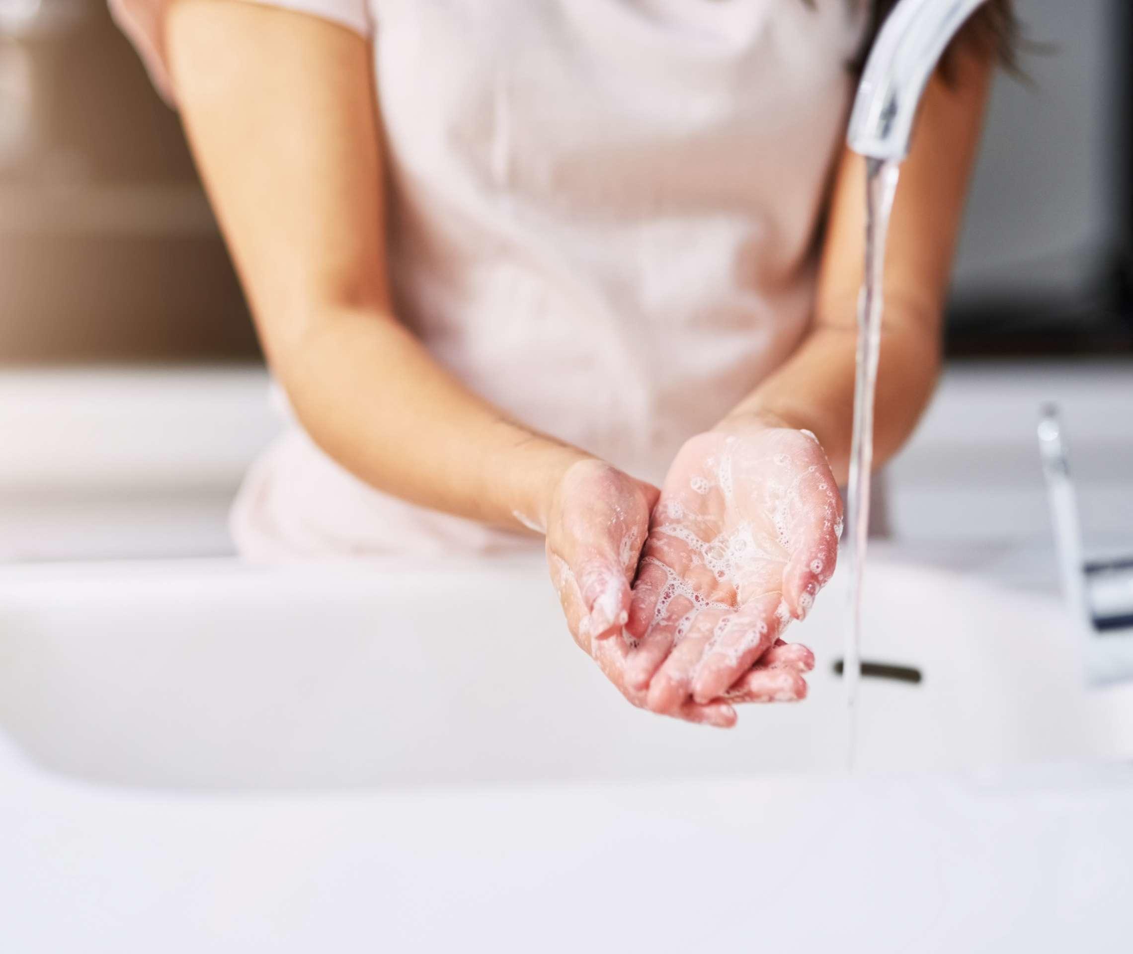 Eine Frau wäscht ihre Hände unter einem Wasserhahn