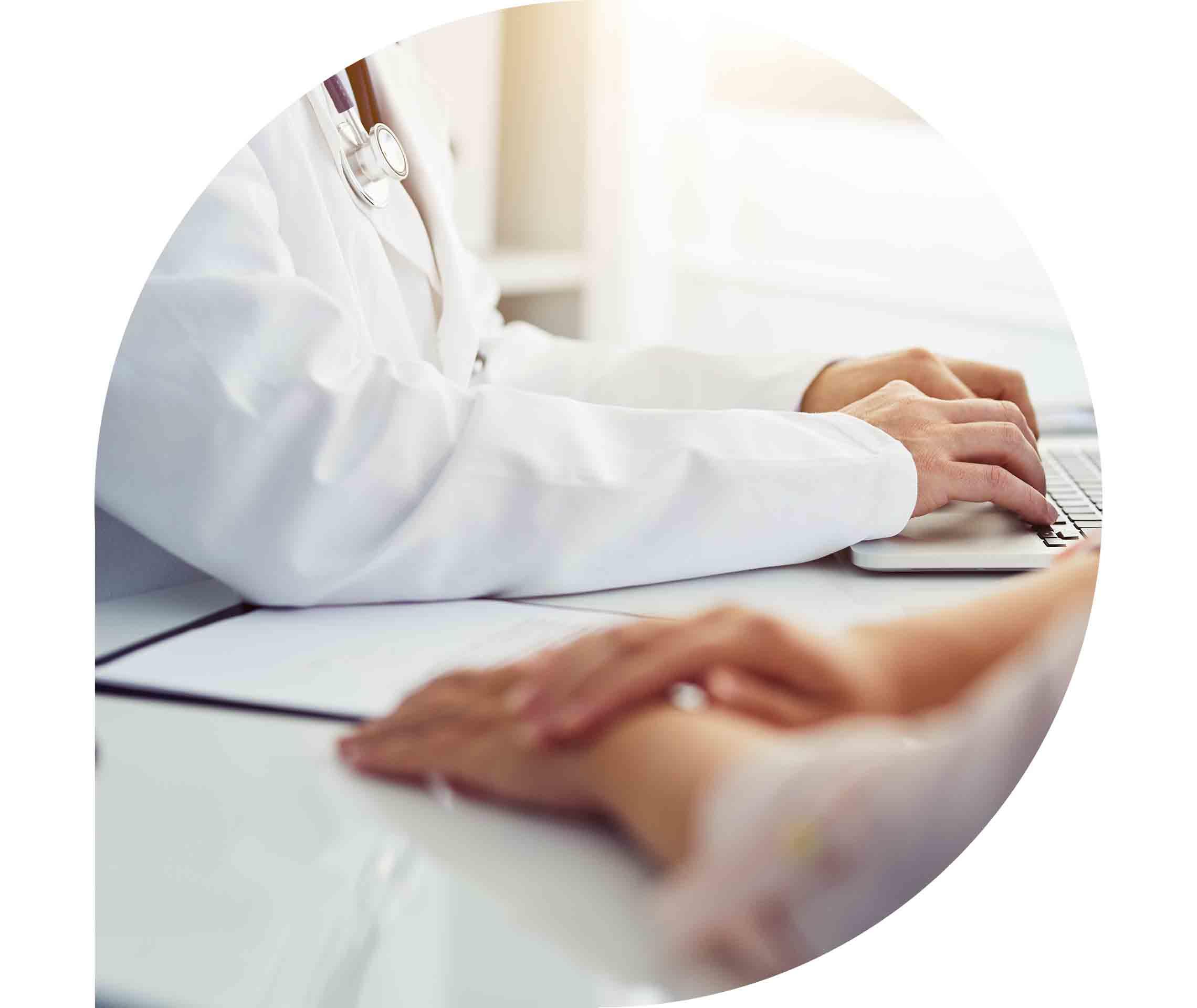 Arzt sitzt mit dem Patienten am Schreibtisch und schreibt etwas auf dem Laptop