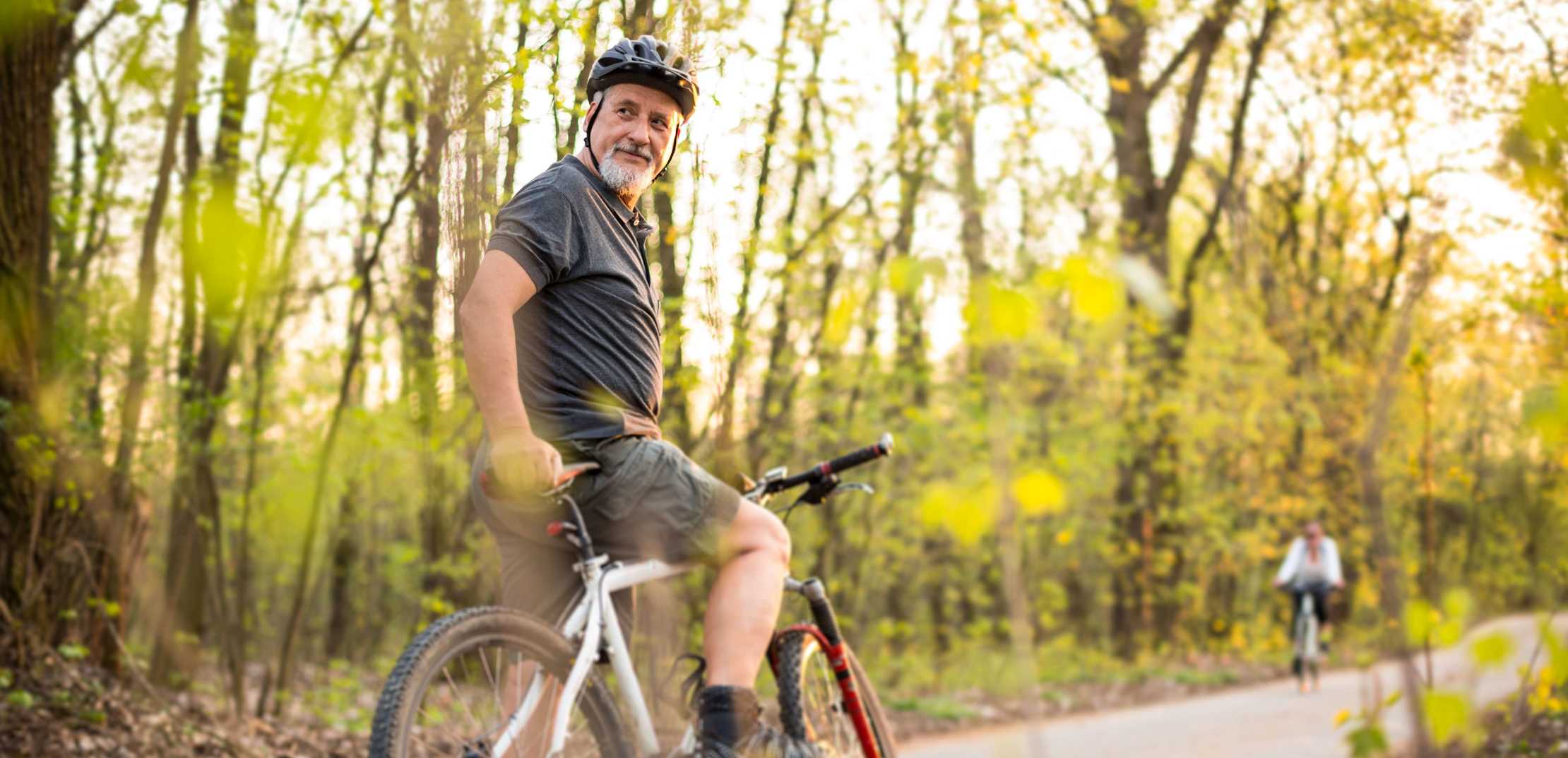 Mann mit Bart und Helm hat mit seinem Fahrrad angehalten und dreht sich um