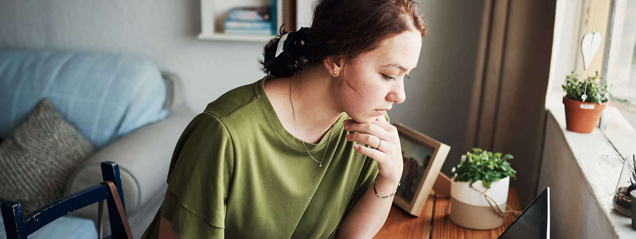 Junge Frau sitzt an ihrem Schreibtisch und arbeitet am Laptop