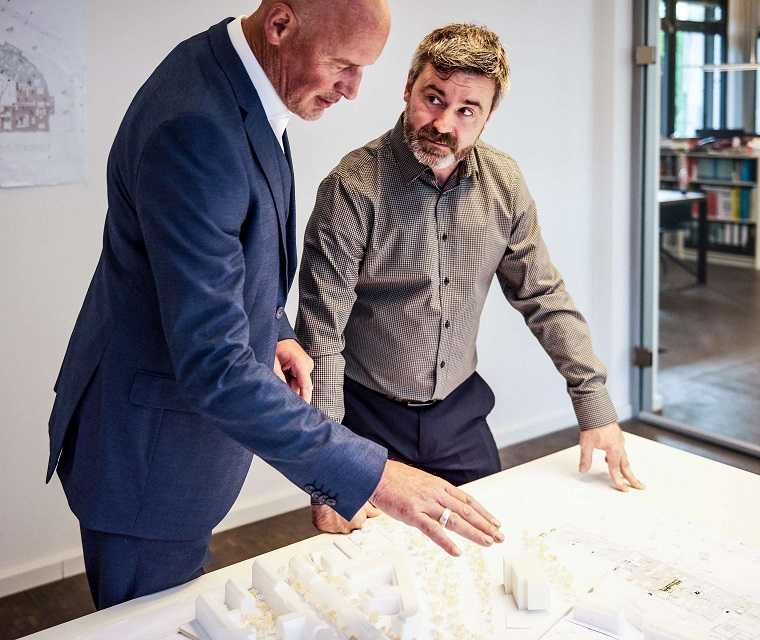 Morbus Bechterew Patient Michael und sein Chef Martin besprechen sich bei der Arbeit Morbus Bechterew Patient Michael und sein Chef Martin besprechen sich bei der Arbeit