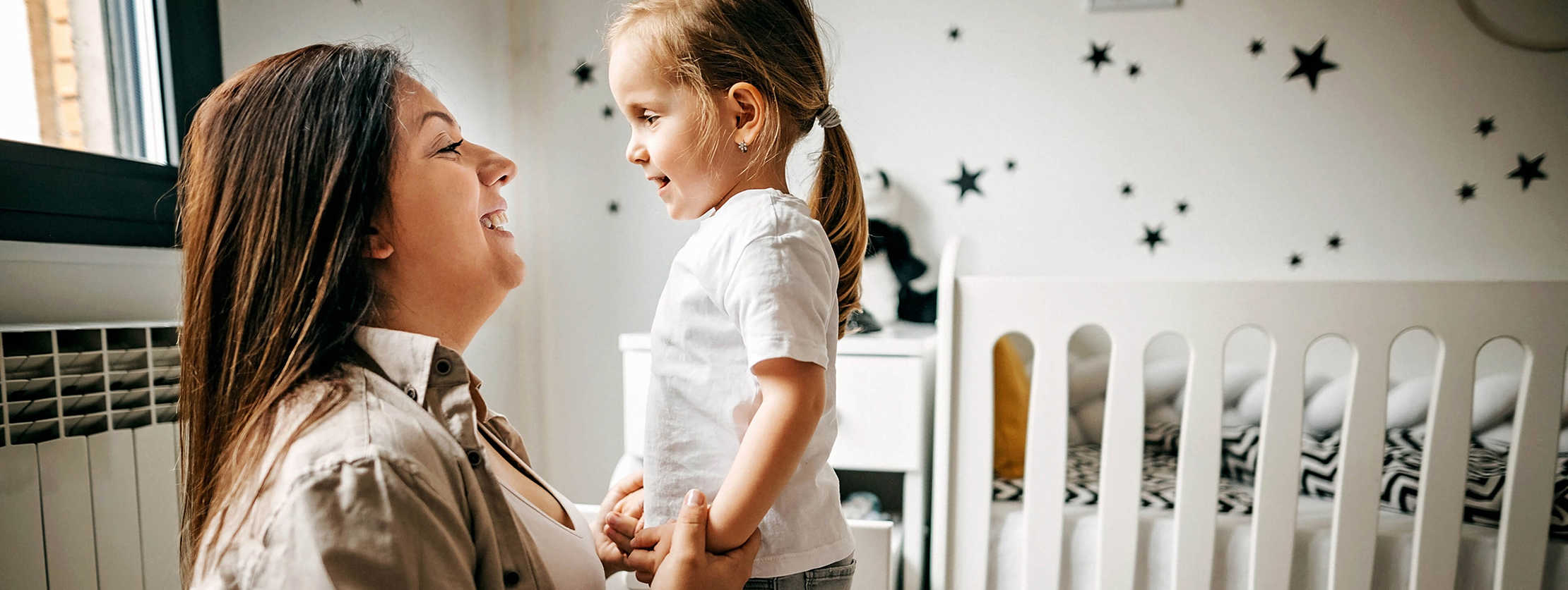 Mutter kniet vor ihrer Tochter und sie lachen sich an