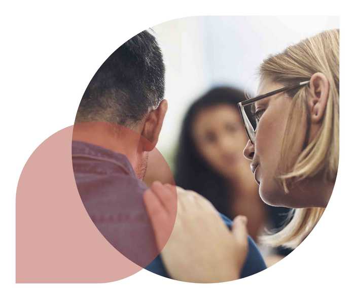 Eine Frau ermutigt einen Mann und fasst ihm auf die Schulter