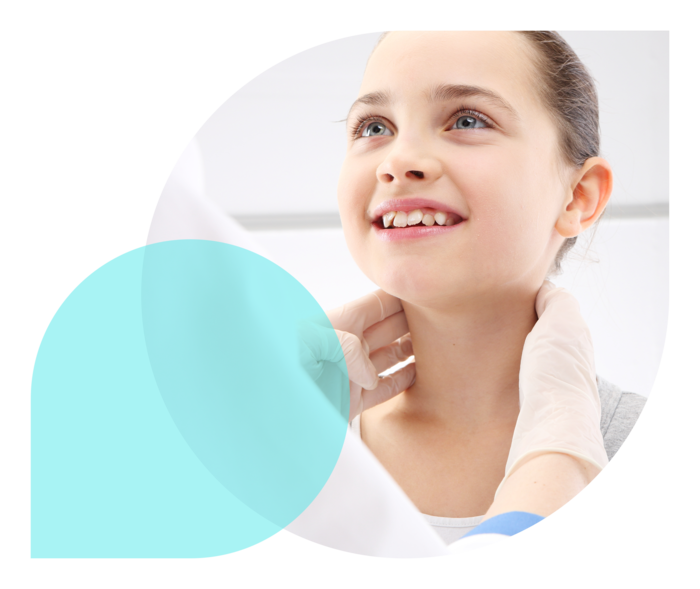 Eine Ärztin tastet die Halswirbelsäule eines Mädchens ab, das lächelt