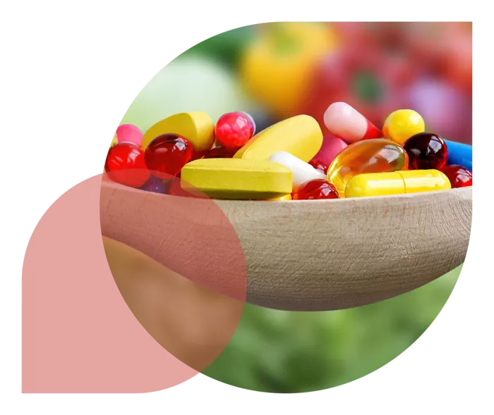 Ein Holzlöffel gefüllt mit bunten Kapseln und Tabletten.