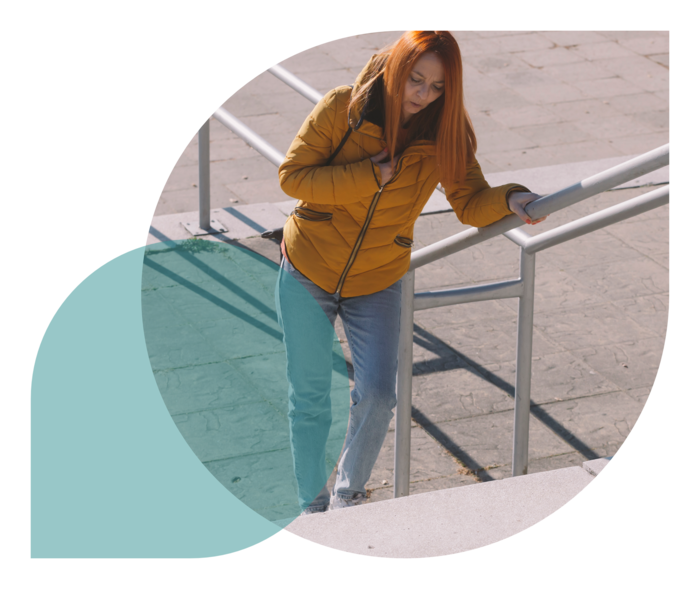 Eine Frau steigt eine Treppe herauf und wirkt erschöpft.