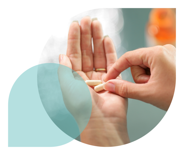 Ein Person nimmt eine Tablette von ihrer linken Handfläche.