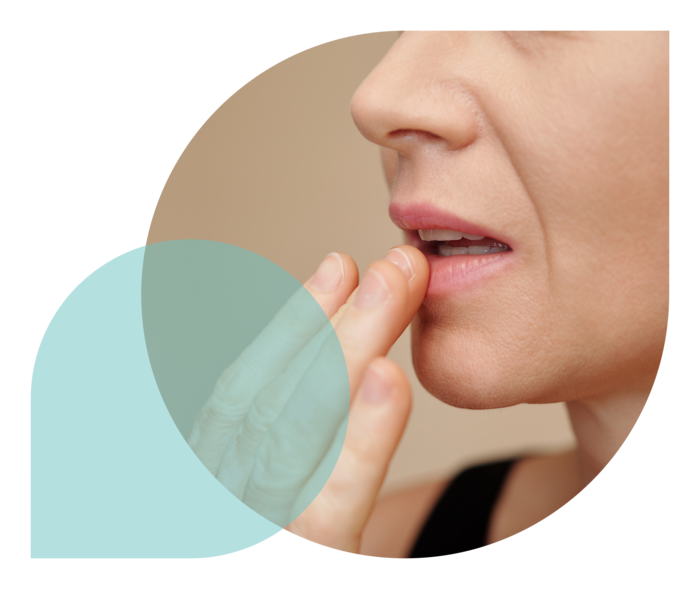 Eine Frau streicht sich über ihre spröde Unterlippe.