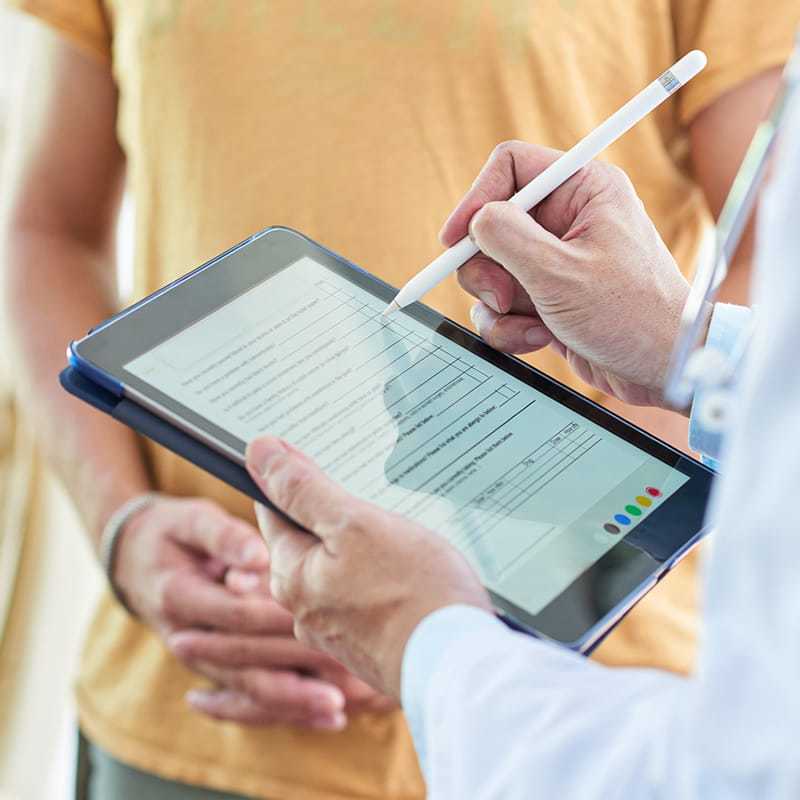 Ratgeber Rheuma: Eine Ärztin notiert sich auf einem Tablet Angaben eines Patienten