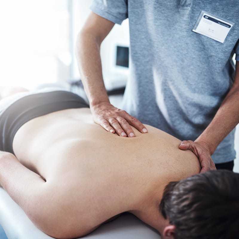Ratgeber Rheuma: EIn Physiotherapeut massiert einem liegenden Man die linke Schulter