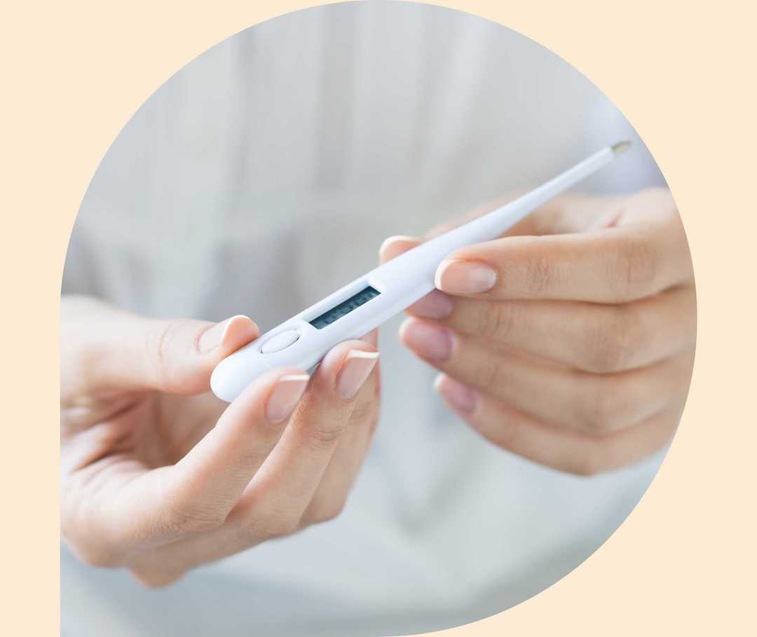 Ratgeber Rheuma: Eine Medizinerin schaut auf ein Fieberthermometer