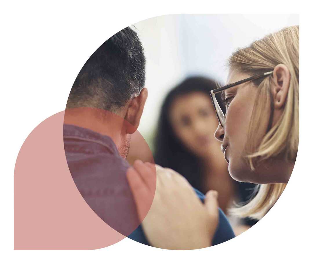 Eine Frau ermutigt einen Mann und fasst ihm auf die Schulter