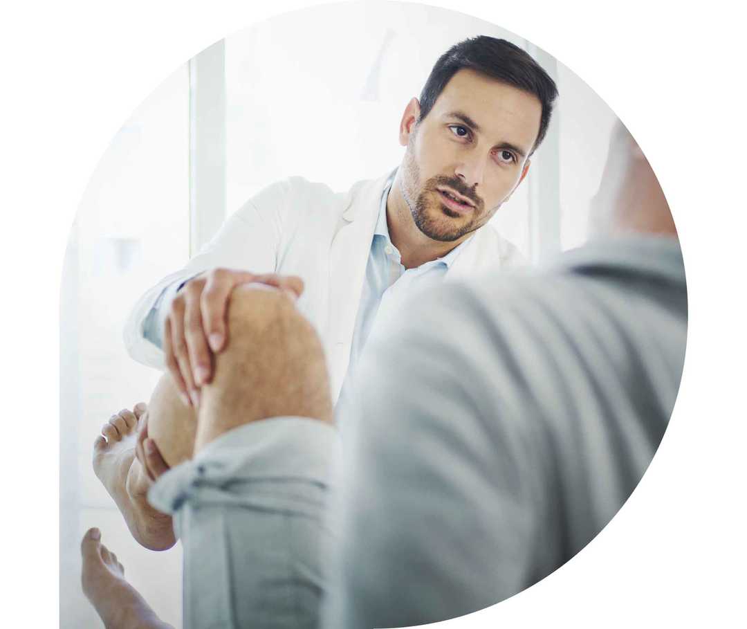 Ratgeber Rheuma: Ein Physiotherapeut behandelt das Knie eines Patienten