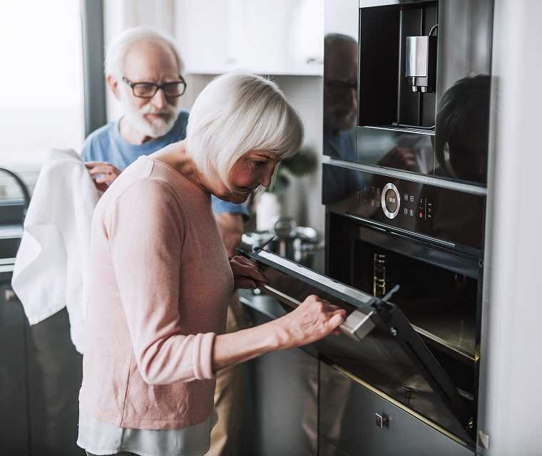 Älteres Paar ist zusammen in der Küche und macht sauber