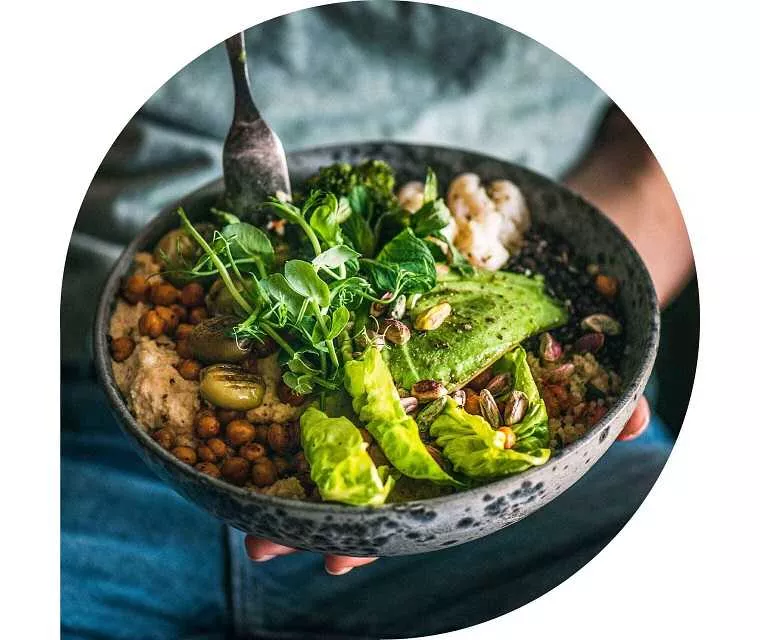 Eine Gabel sticht in eine Schüssel mit Gemüse und Salat.