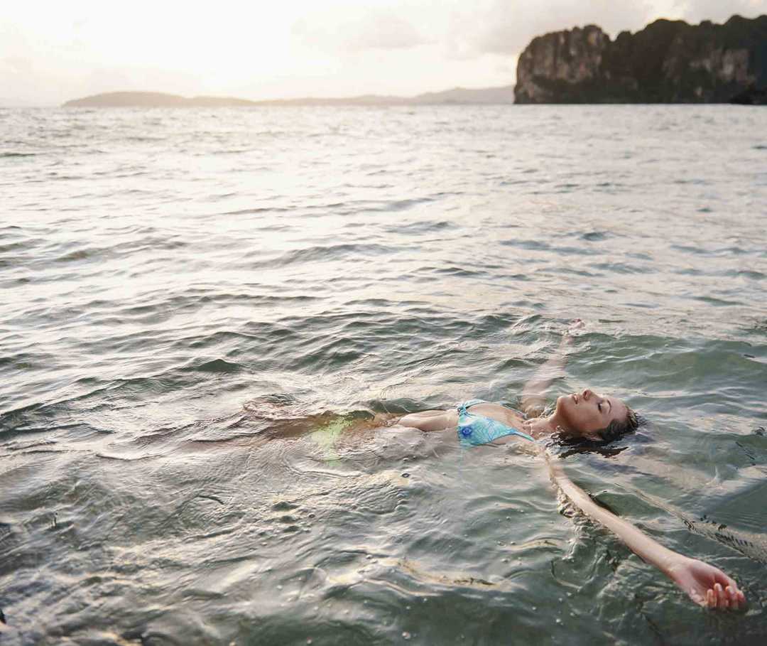 Ratgeber Rheuma: Eine an Morbus Bechterew erkrankte Frau lässt sich auf dem Rücken liegend im Wasser treiben