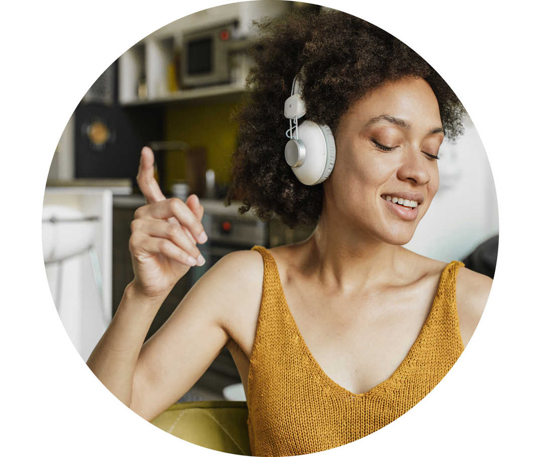 Dunkelhaarige Frau sitzt mit Kopfhörern auf dem Sofa