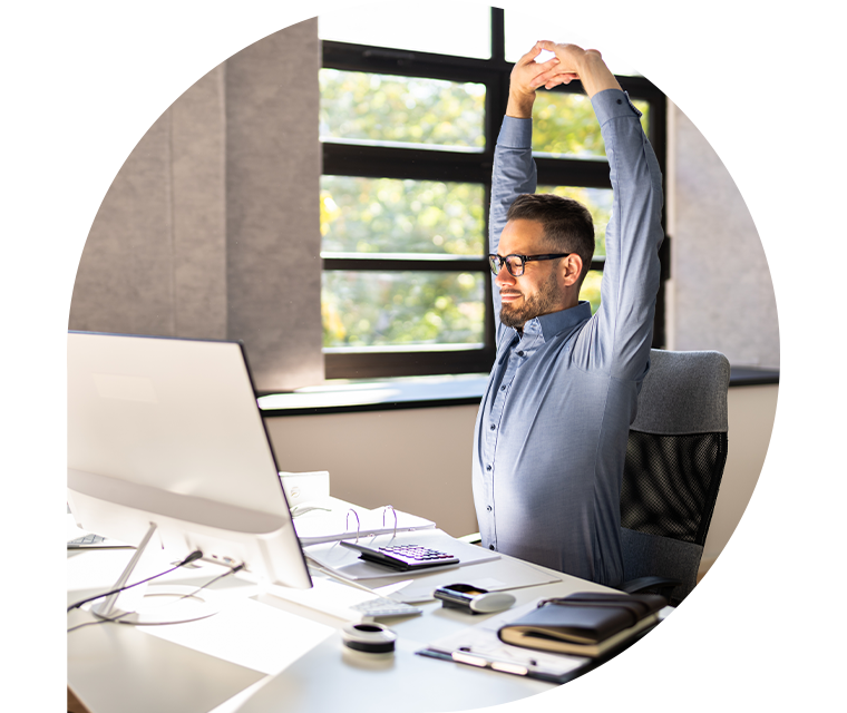 Ratgeber Rheuma: Ein Mann am Schreibtisch macht eine Pause und reckt seine Arme nach oben
