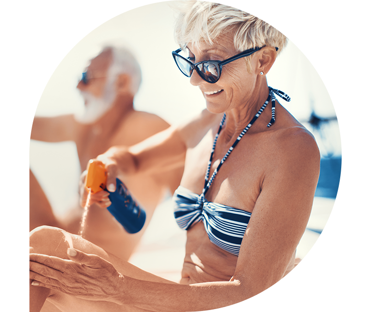 Ratgeber Rheuma: Eine Frau sitzt am Strand und cremt sich zum Schutz vor UV-Strahlung ein