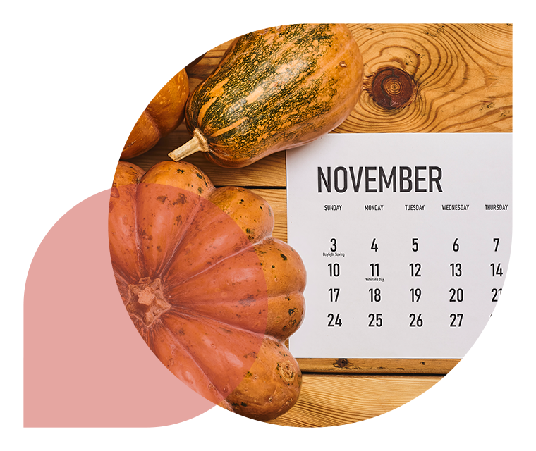 Drei Kürbisse und Kalender liegen auf einem Holztisch