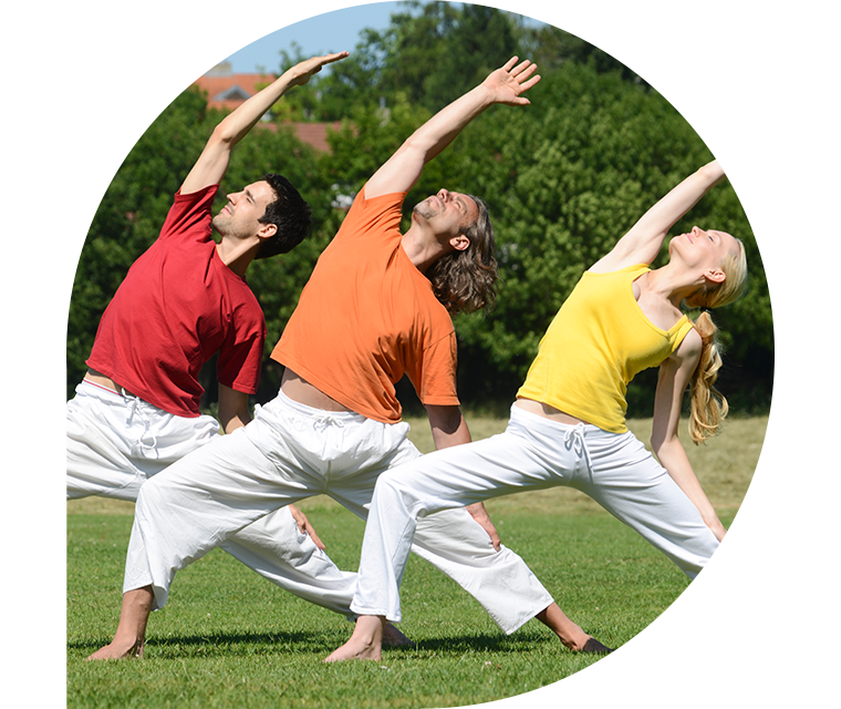 Zwei Männer und eine Frau beim Yin-Yoga auf einem grünen Rasen