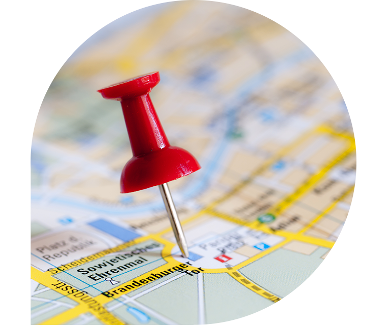 Eine Stecknadel markiert auf einer ausgebreiteten Landkarte das Brandburger Tor in Berlin