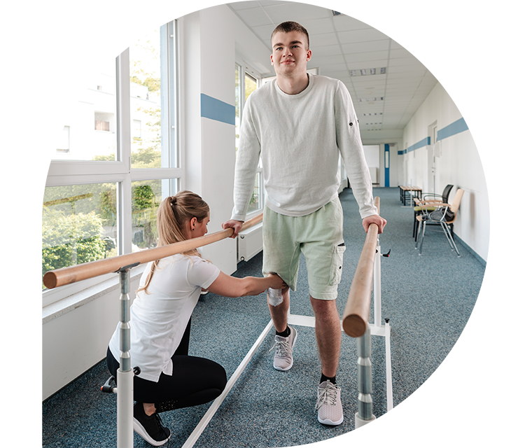 Eine Physiotherapeutin hilft einem Patienten bei Gehübungen