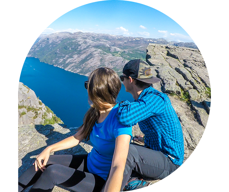 Ratgeber Rheuma: Ein Paar sitzt auf dem 604 Meter hohen Felsen „Preikestolen“ und schaut auf den Lysefjord in Norwegen.