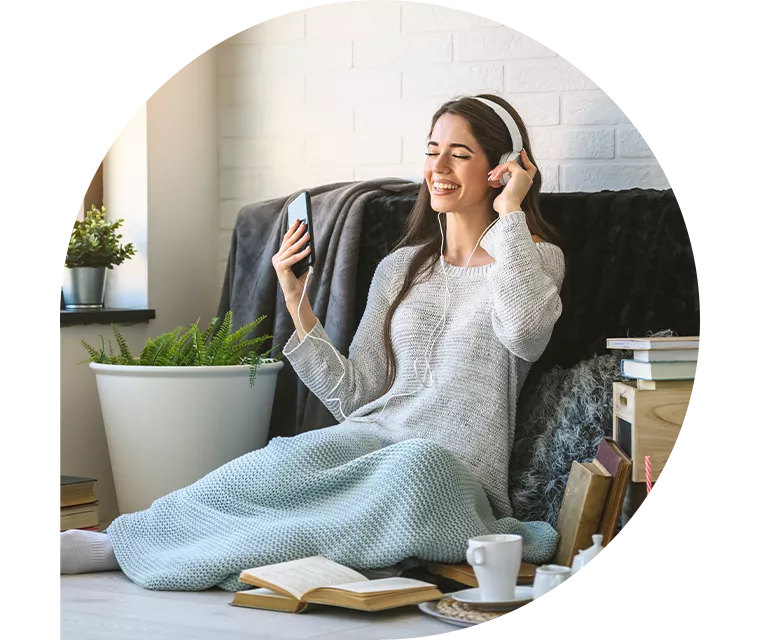 Eine Frau genießt bei Musik, Kaffee und einem Buch den Tag