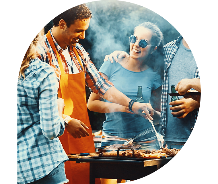 Junge Leute stehen um einen Grill. Einige haben Bierflaschen in der Hand