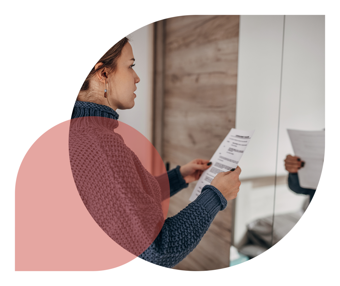 Frau hält einen Zettel in der Hand und schaut sich im Spiegel an