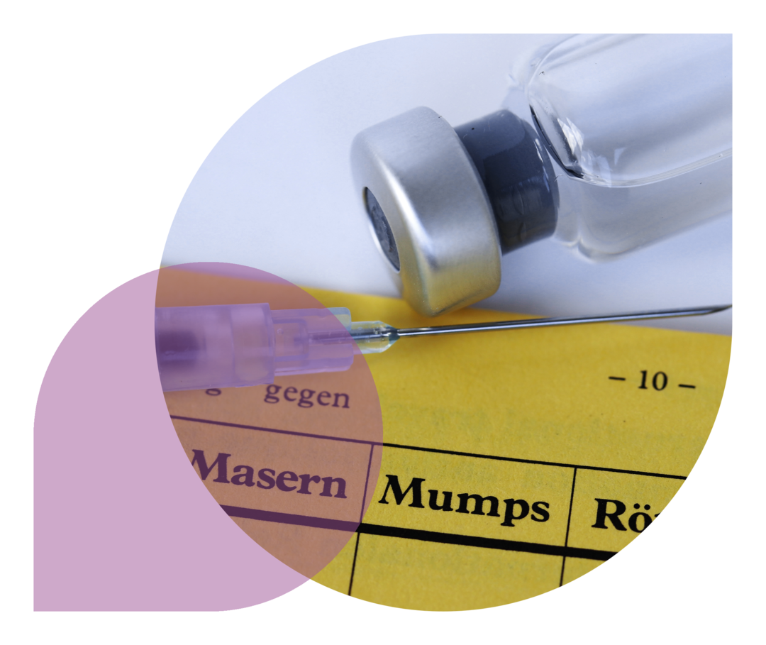 Auf einem Impfausweis liegen eine Spritze und eine Flasche mit dem Impfserum