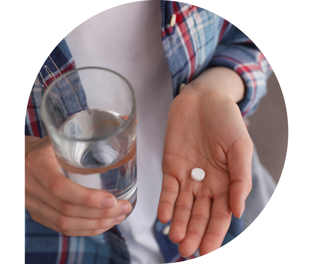 Ein Glas Wasser und eine Pille in der Hand 