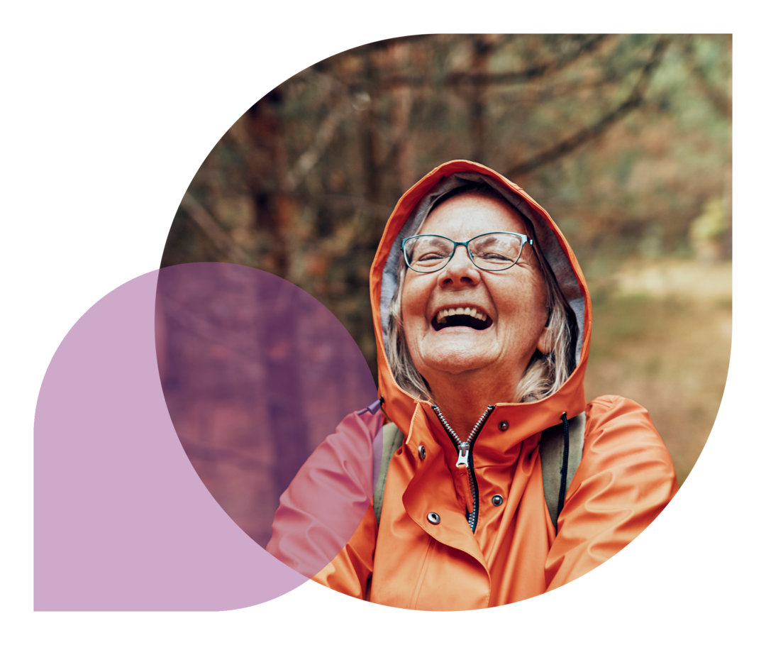 Ratgeber Rheuma: Eine ältere Dame im Regenmantel freut sich