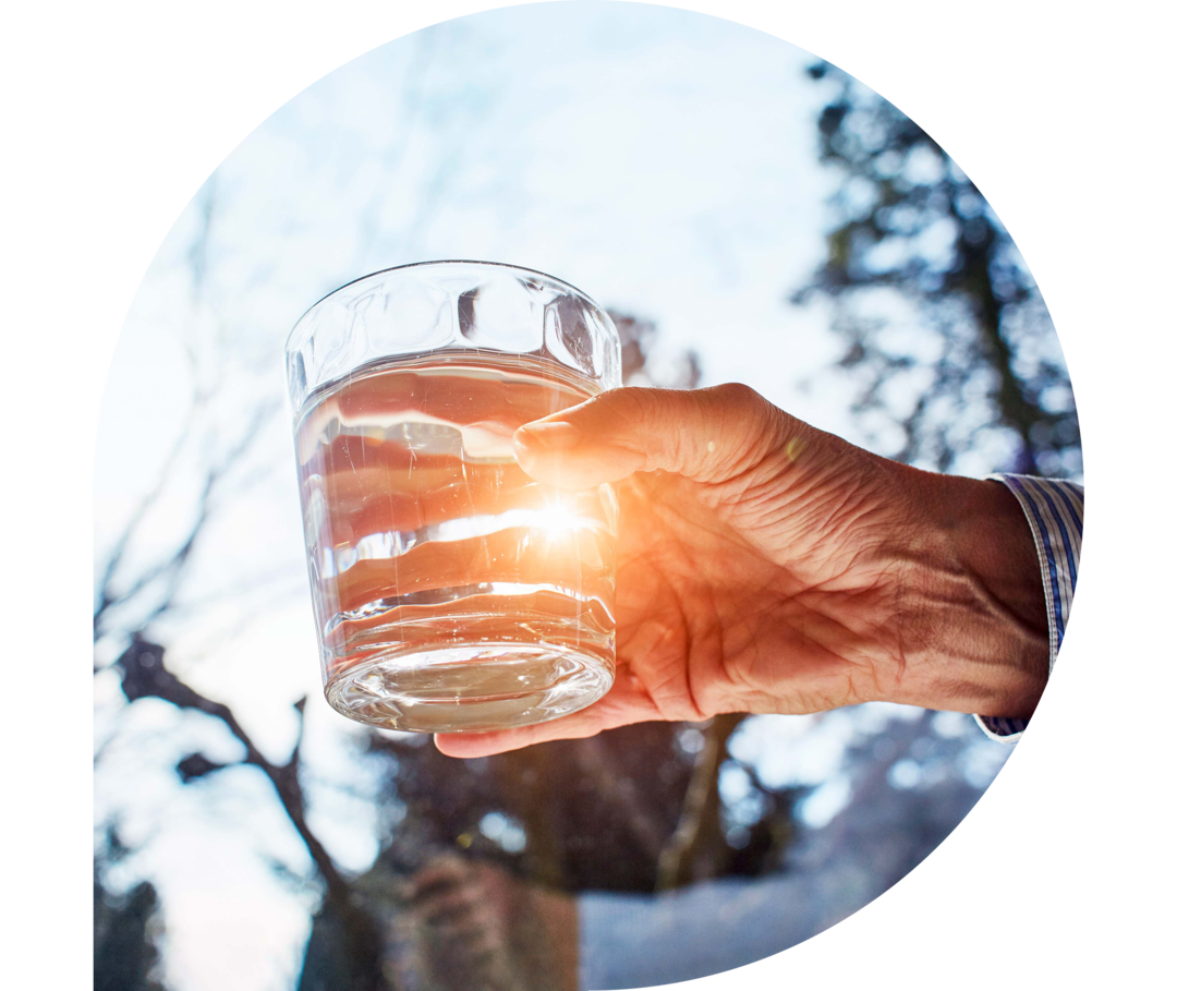 Ratgeber Rheuma: Eine ältere Hand hält ein mit Wasser gefülltes Glas