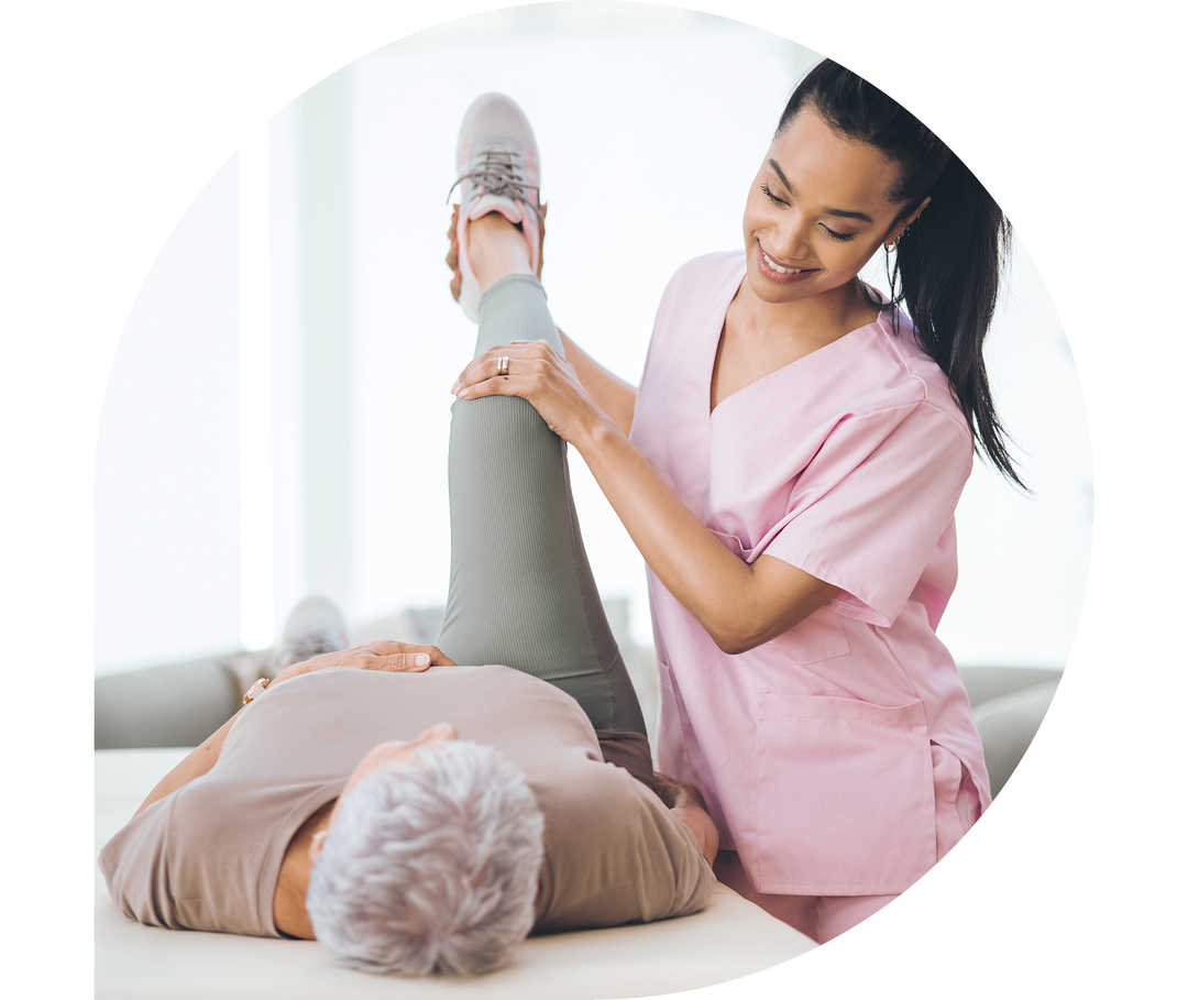 Eine Physiotherapeutin arbeitet mit einer Patientin, die auf einer Liege liegt. 