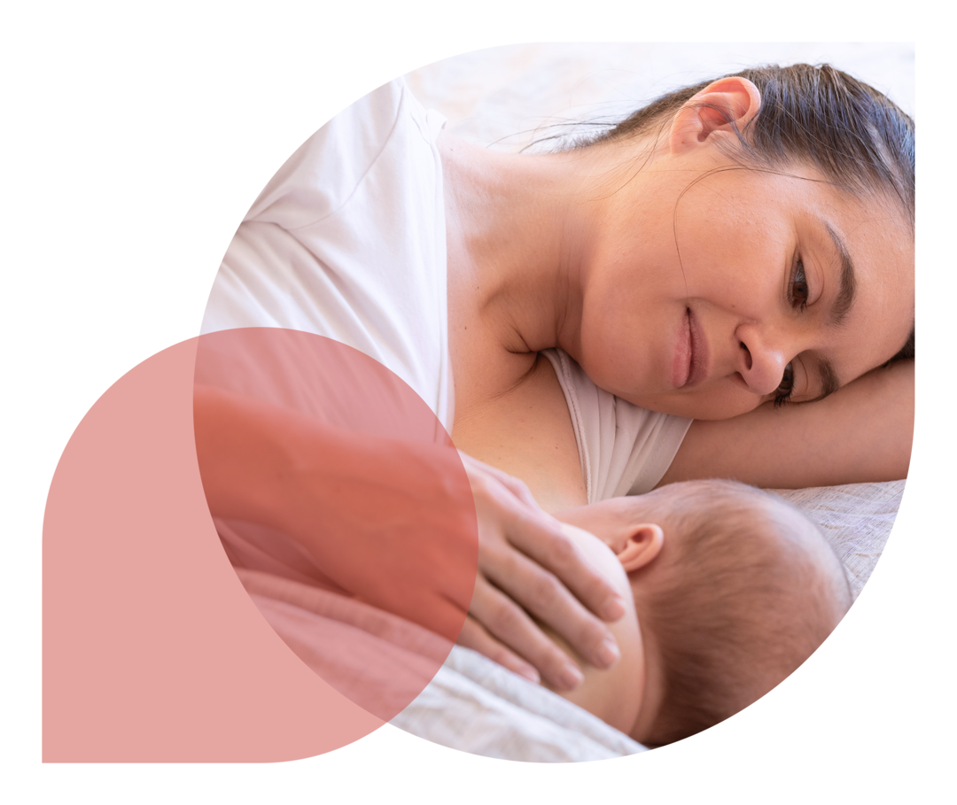 Eine Frau stillt ihr Baby im Bett.