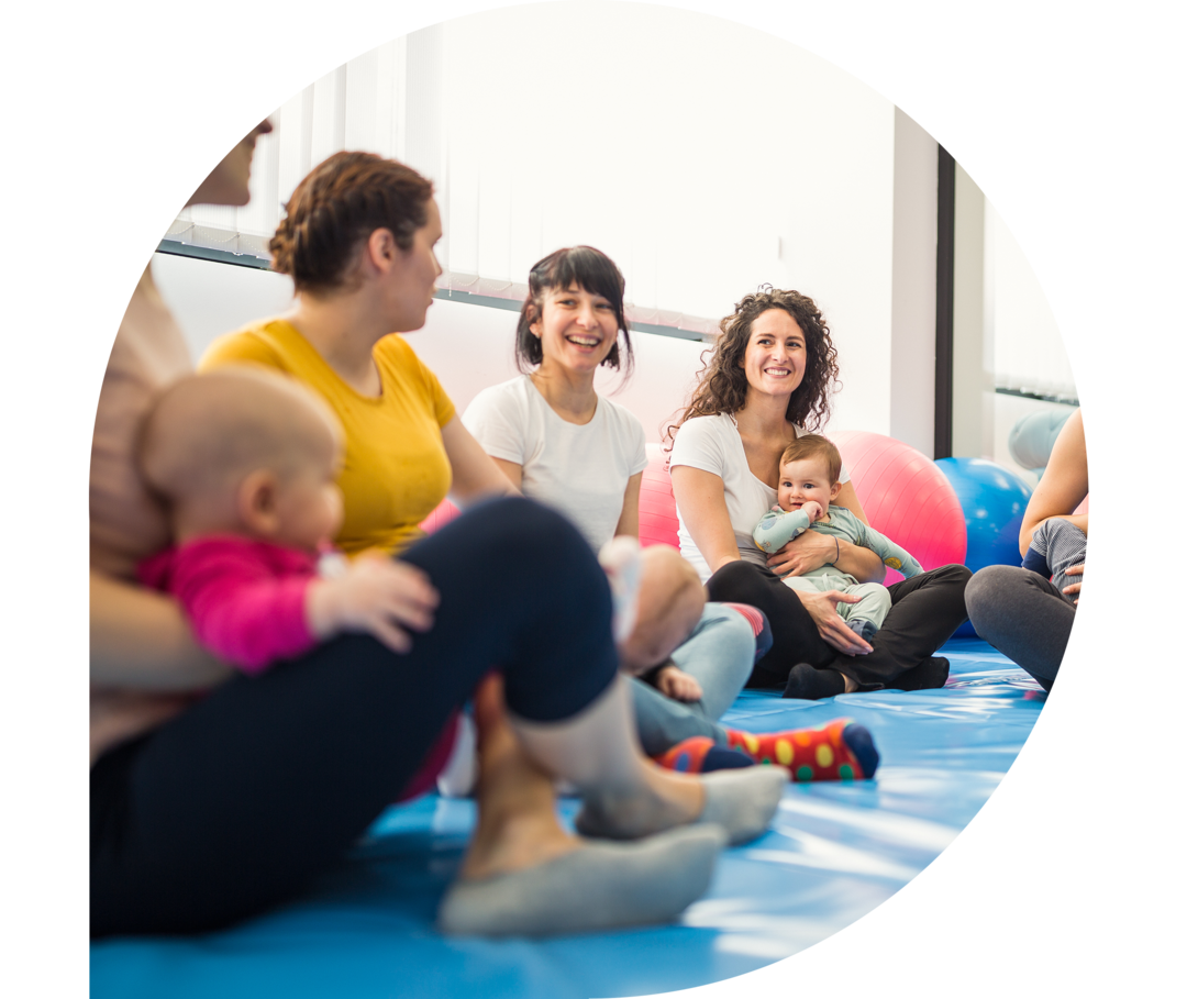 Eine Gruppe Mütter mit Babys in einem Gymnastikraum.