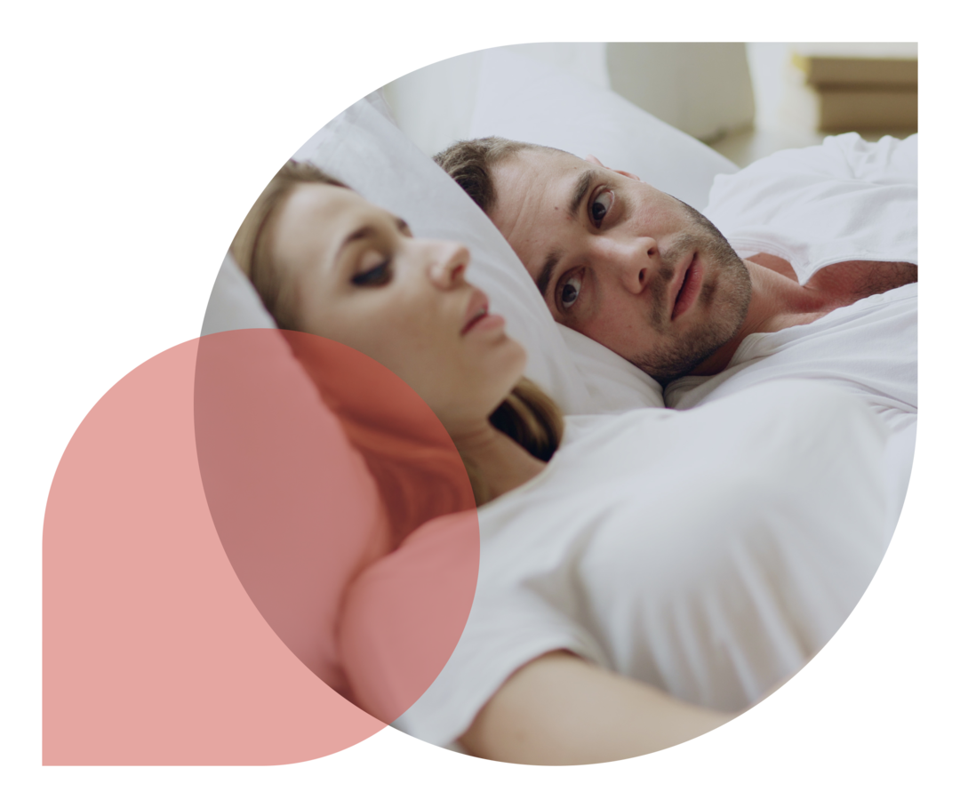 Ein Paar liegt im Bett und unterhält sich mit ernster Miene.