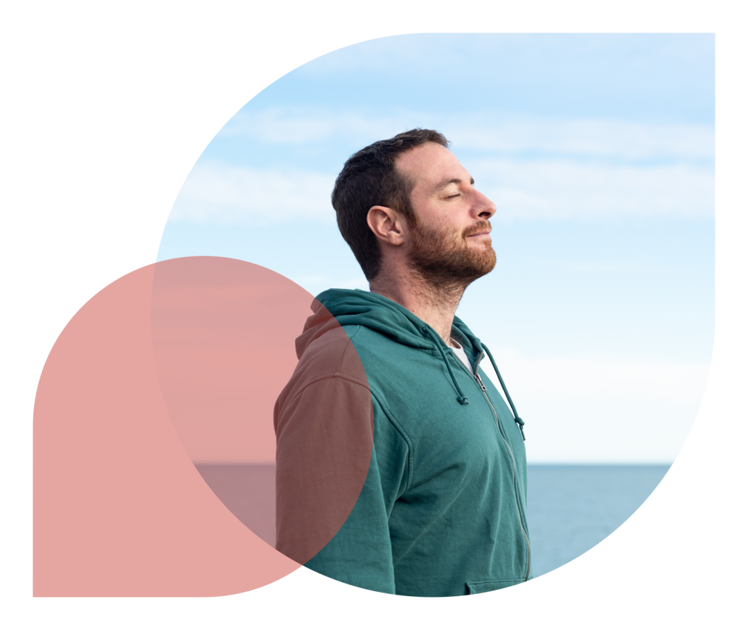 Ein Mann steht mit geschlossenen Augen am Meer.