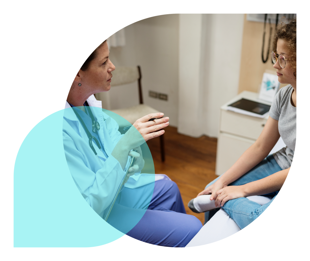 Ratgeber Rheuma: Ablauf der Transition Eine Ärztin im Gespräch mit einer jugendlichen Patientin in einem Behandlungszimmer.