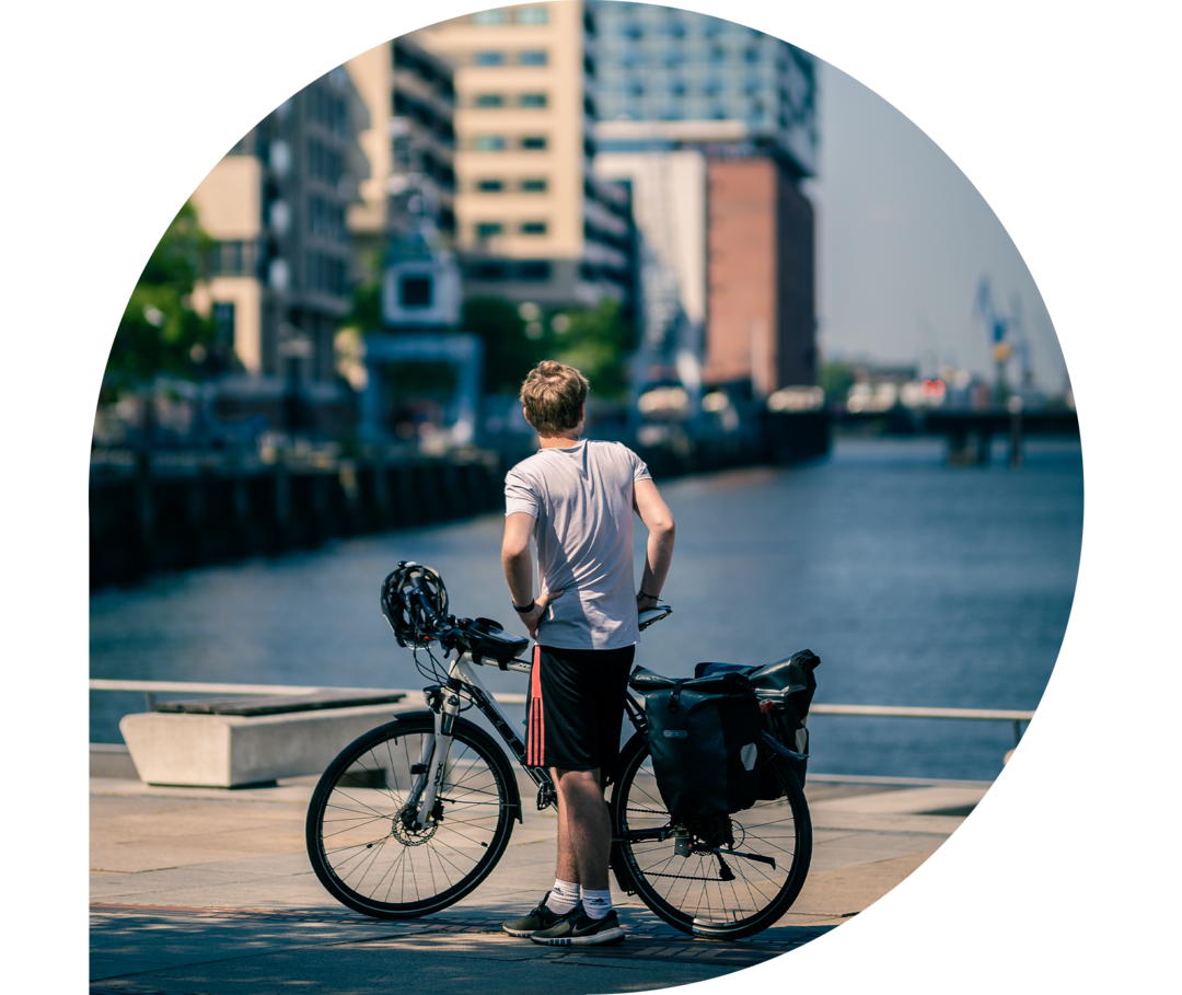 Ratgeber Rheuma: Rückansicht Phil Oliver Ladehof Phil Oliver Ladehof steht mit seinem Fahrrad mit dem Rücken zur Kamera und schaut auf Wasser.