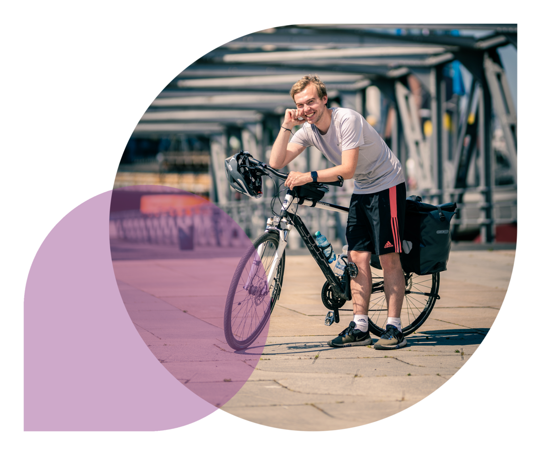 Phil Oliver Ladehof stützt sich auf seinem Fahrradlenker und lacht in die Kamera.