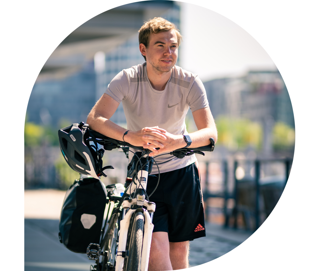 Phil Oliver Ladehof stützt sich auf seinen Fahrradlenker und schaut mit erwartungsvollem Blick.