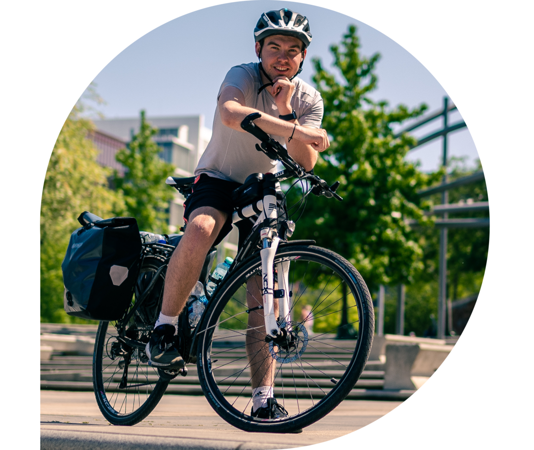 Ratgeber Rheuma: Phil Oliver Ladehof auf Tour mit dem Rad Phil Oliver Ladehof trägt ein weißes Shirt und sitzt fahrbereit auf einem Fahrrad.