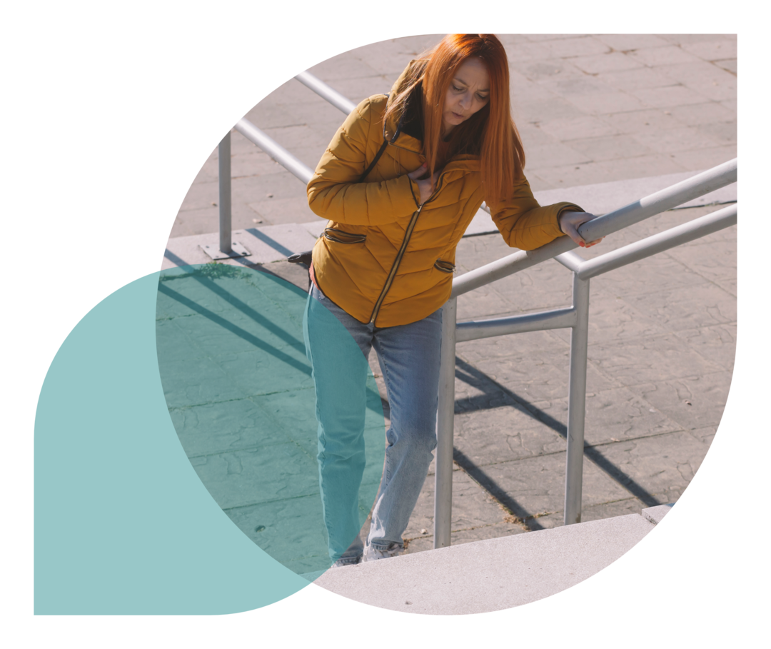 Eine Frau steigt eine Treppe herauf und wirkt erschöpft.