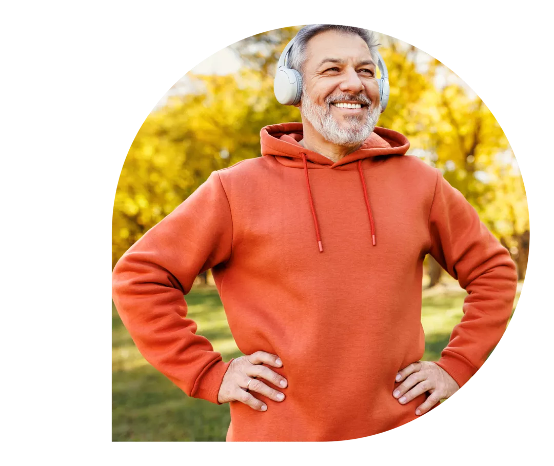 Ein Mann steht lächelnd in einem Park.