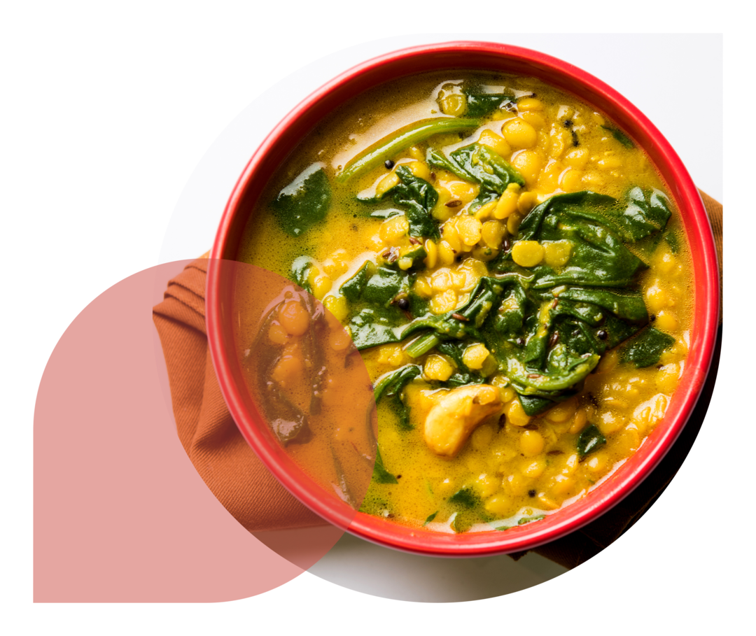 Auf einer Serviette steht eine rote Schale mit einem Linsengericht.